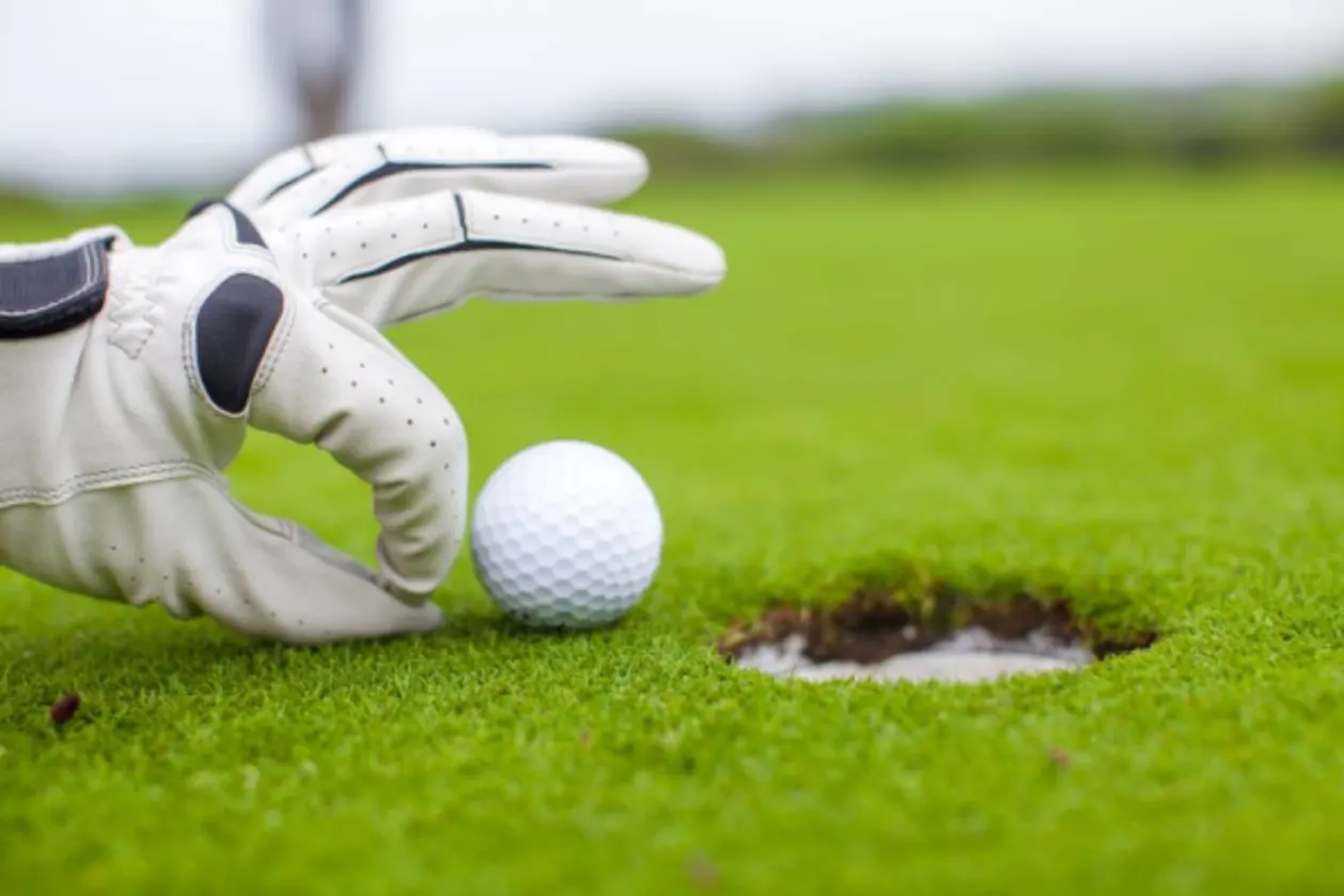 Golf player pushing golf ball into the hole